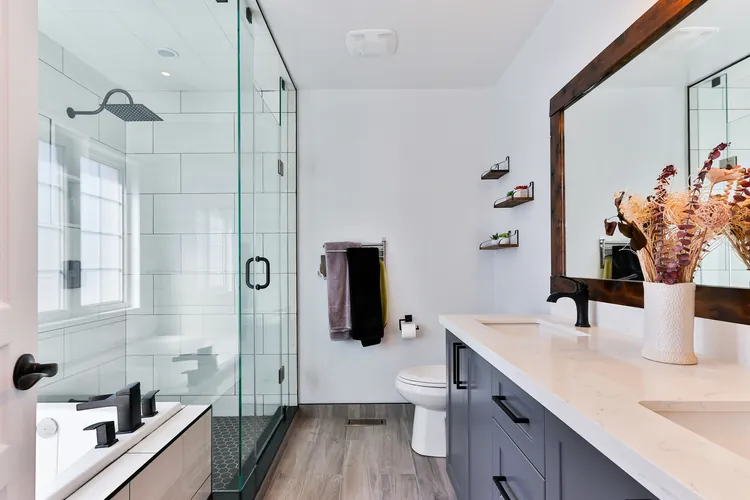 Bright bathroom with a glass-walled shower, a double vanity, and black fixtures