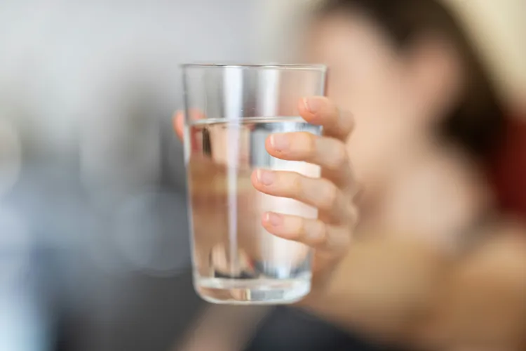 Hand holding out a clear glass of water